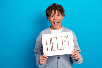 Excited schoolboy holding a help sign, expressing emotion on a vibrant blue background, showcasing...