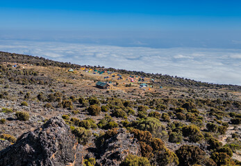  Altitude camp on kilimanjaro mountain with tents and huts above the clouds.