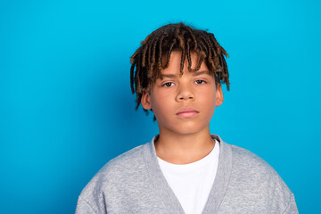 Portrait of a confident young boy with dreadlocks smiling against blue background wearing casual...