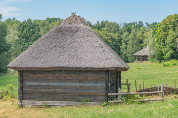 Traditional wooden house with conical thatched roof in an ancient Central European forest village,...