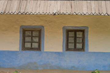Traditional blue-beige Central European village building, with three windows and a diagonal...