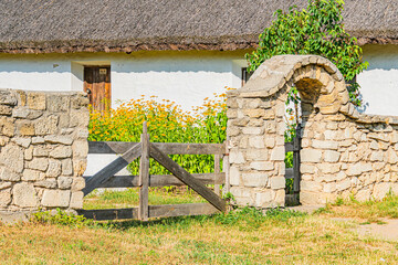 An old stone farm building possibly barn or stable with a curved wooden door frame and open metal...