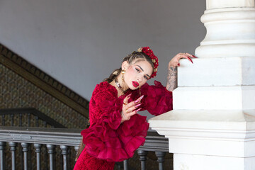A beautiful woman dancing flamenco leaning against a white column in a square in Seville, Spain....