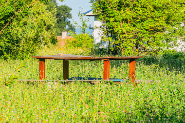 Naklejka premium Tranquil, daytime scene of an ancient Central European village Grassy foreground with picnic table, undulating green landscape, brick chimney structure in the distance