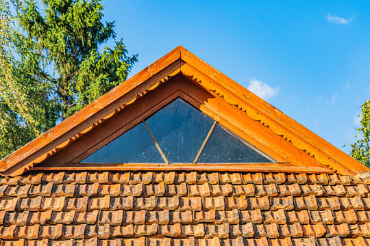 Close-up of a Central European building with distinctive dark shingled roof and triangular window Natural lighting, muted color palette, shallow depth of field, symmetry, geometric forms