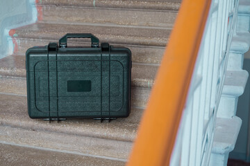 Rugged black hard case designed for tools or sensitive equipment, placed securely on worn steps in...