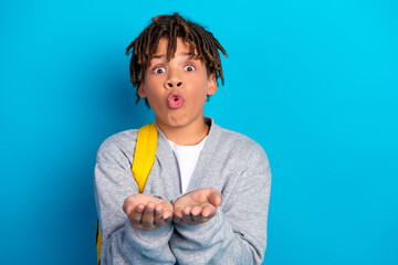 Surprised child holds hands out gesturing on blue background, schoolboy in casual grey attire with...