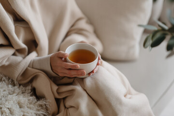 Person enjoying a cup of tea, wrapped in a cozy blanket, creating a peaceful moment.