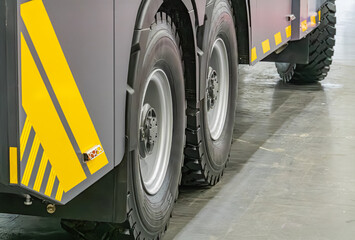 Gray, robust truck on reflective concrete floor Angular design with black treaded tires in hubcaps,...