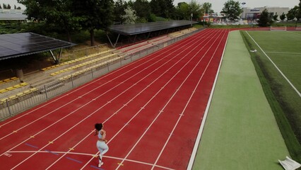 Fototapeta premium Jogging around the stadium, drone view. The woman is engaged in professional running