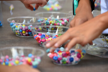children's hands select multi-colored beads in bulk, bright balls of different shapes, craft...