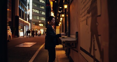 An elegant woman takes a disposable container with ready-made food and walks down the street of the...