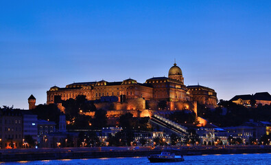 Fototapeta premium Buda castle illuminating the danube river at twilight in budapest