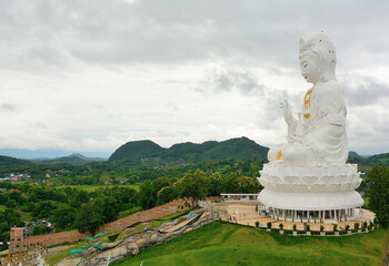 White guan yin statue overlooking green valley in thailand
