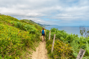 Tourist walking along the scenic route to sakoneta beach in zumaia, basque country