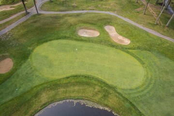 Aerial view of a golf course with green and bunkers.