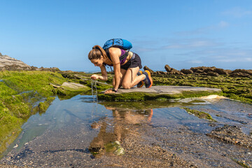 Hiker refreshing at sakoneta beach flysch in zumaia, basque country