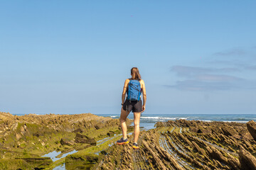 Hiker exploring zumaia flysch cliffs on sakoneta beach, basque country