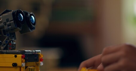 A boy builds a robot from a construction kit while sitting at a table at home. Close-up of his...