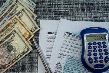U.S. tax return forms with cash, pen, and calculator for annual income reporting 2025