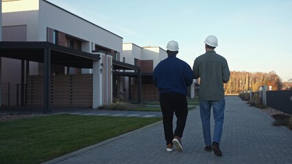 Foremen inspect the finished houses and talk. Rear view