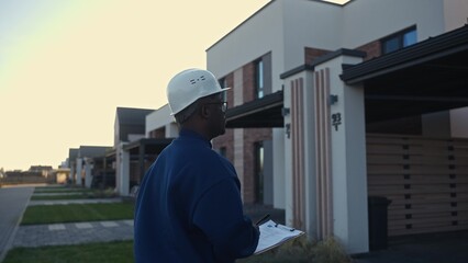 The foreman evaluates the finished object standing near the house