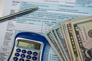 Financial planning with tax forms, cash, and calculator on desk during income reporting season