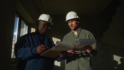 Two men in hard hats at a construction site. They are talking while discussing the renovation