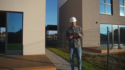 The construction engineer looks up from his notebook and smiles at the camera.