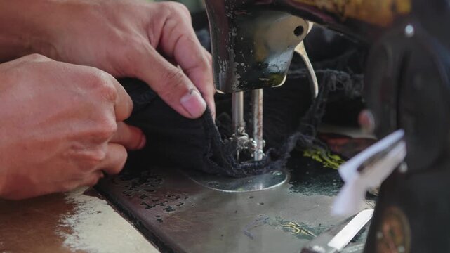 Adult male tailor sewing clothes using vintage sewing machine, shot in outdoor environment. 4K 30 fps (frame per second), 2x slow motion 