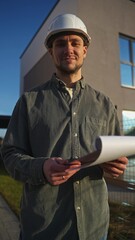 Portrait of a man in the construction caste and with a notebook in his hands near the house