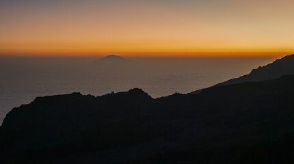 Mount Meru emerging from a sea of clouds at sunset in tanzania