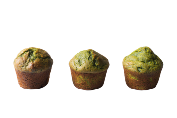 three muffins with green toppings on a white surface