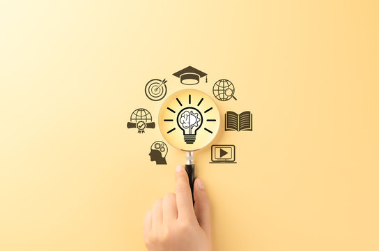 Innovative Learning and Knowledge Development Concept. Magnifying glass over glowing light bulb symbol with brain, representing education, global learning objectives, creativity, and e-learning. learn