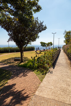 Caminho de acessibilidade com &aacute;rvores e vista para a cidade de Belo Horizonte no Mirante das Mangabeiras durante um lindo dia ensolarado