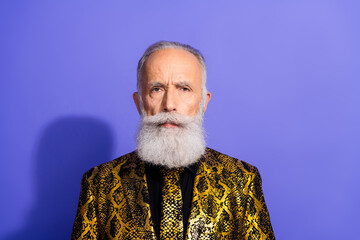 Stylish elderly man in vibrant patterned suit posing confidently against a purple studio background
