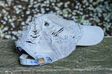 one old cotton torn blue white baseball cap with holes lies on a gray table on a summer street