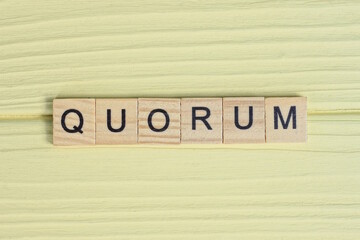 the gray word quorum of gray small wooden letters lie on a yellow table