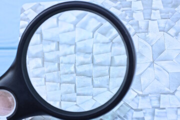 one large black magnifying glass magnifies the white pattern on the box lid