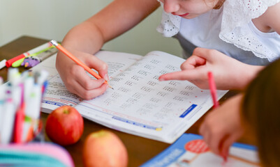 A young girl focuses on solving math problems in her workbook during a homeschool lesson. Ideal for concepts of homeschooling, independent learning, and early education.