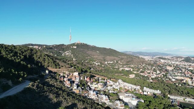 Aerial view of Tibidabo Mountain, where the contrast between the lush green forest and the urban sprawl of the city creates a compelling composition, Barcelona, Spain.
