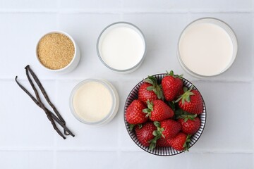Different ingredients for panna cotta. Milk, sugar, vanilla and strawberries on white tiled table,...
