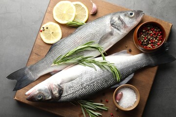 Fresh raw seabass with spices on grey table, top view. Fish and seafood delicacies