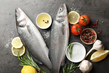 Fresh raw seabass with spices on grey table, flat lay. Fish and seafood delicacies