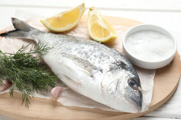Fresh raw dourade with spices on white wooden table, closeup. Fish and seafood delicacies