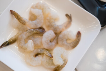 Pile of  raw peeled shrimp on white dish. Top view