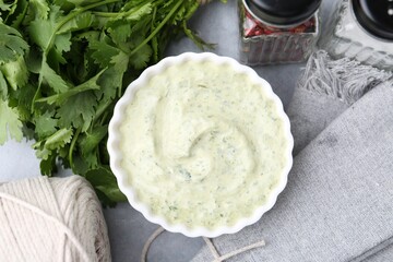 Tasty cilantro sauce in bowl and spices on grey table, flat lay