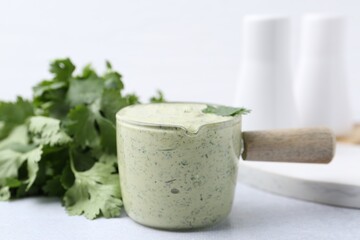 Tasty cilantro sauce on light grey table, closeup