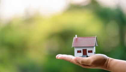 dream home concept miniature house on hand with blurred green nature background idea
