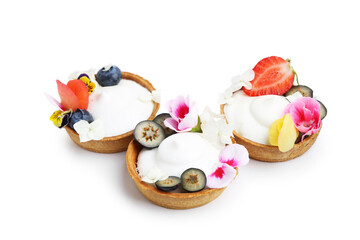 Delicious dessert. Tartlets with cream, berries and flowers isolated on white